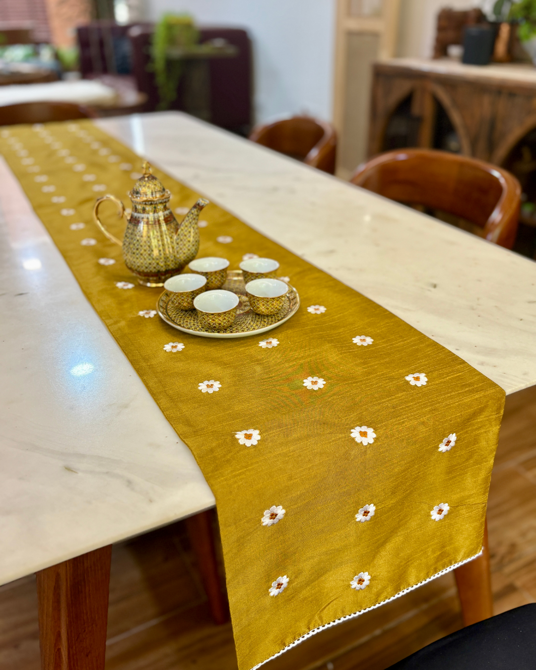 mustard brown table runner with floral patterns on a marble table