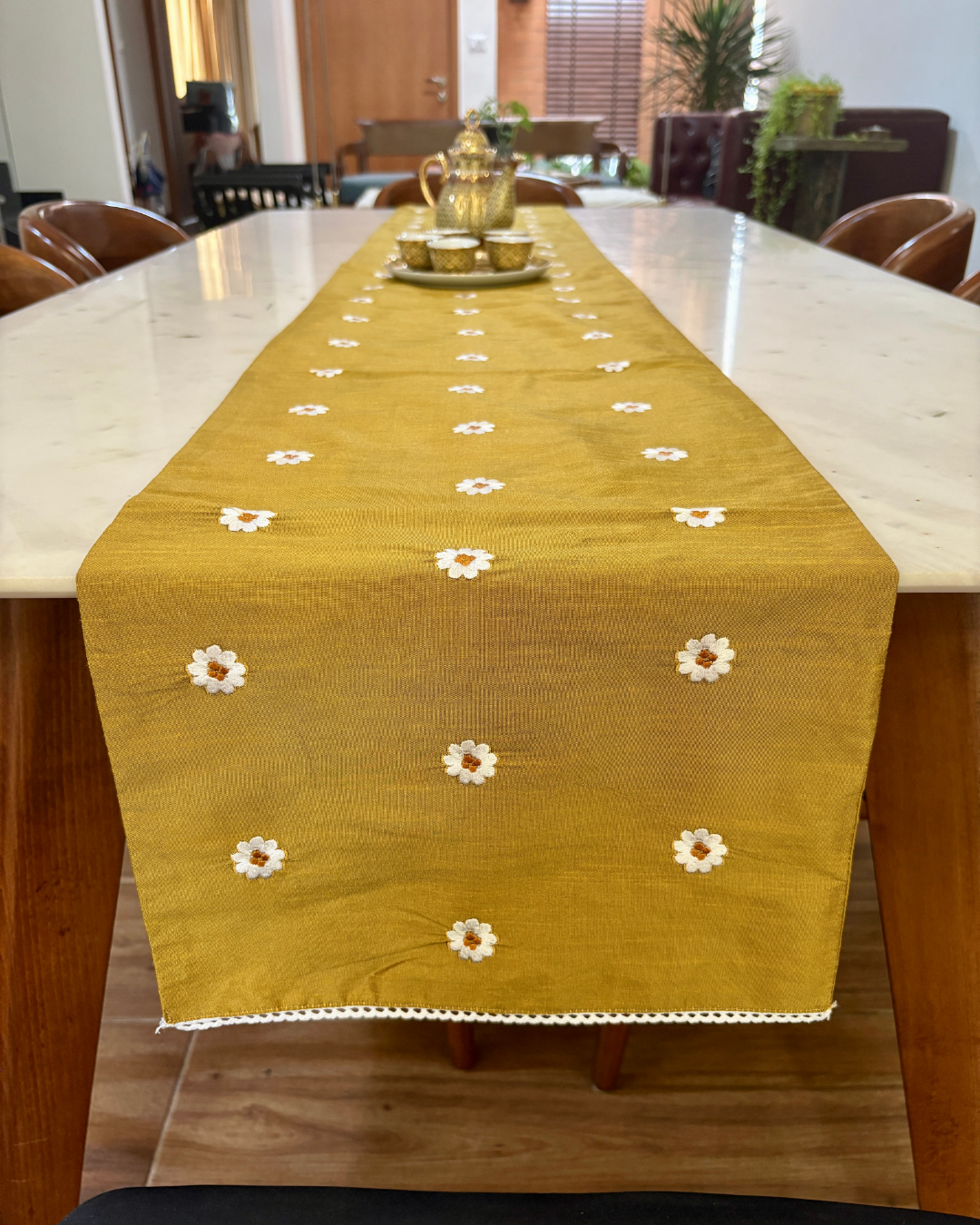 mustard brown table runner with white floral patterns on a dining table.